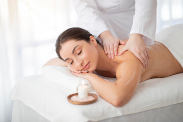 Fototapeta na wymiar Spa Massage. Beautiful Indian Woman Getting Body Treatment By Masseur In Salon