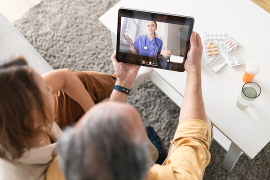 Using eHealth and telemedicine services at home. Senior couple using digital tablet having video call with online doctor