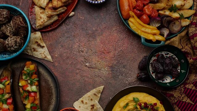 An assortment of different types of authentic Middle East cuisine on a table. Samosa, hummus, baked vegetables, traditional pita bread, olives, pistachios, dates and dried fruits. Copy space