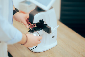 Ophthalmologist Using a Professional Medical Instrument to Measure Eyeglasses. Optometrist at work using professional tools in optical office
