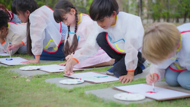 Group of student coloring on painting board outdoors in school garden.
