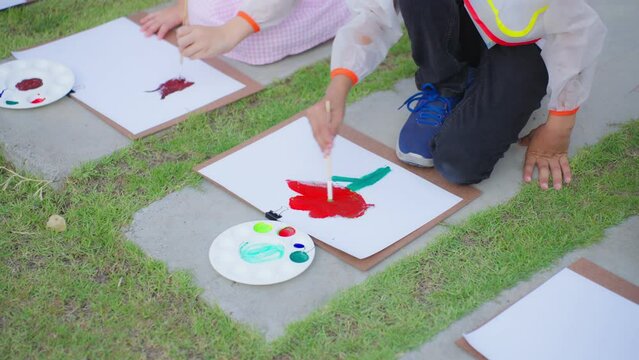 Group of student coloring on painting board outdoors in school garden.