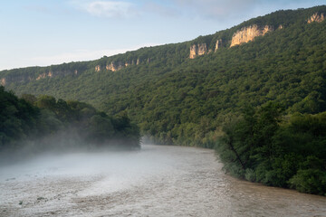 View of the Belaya River and the Una-koz ridge of the Caucasus Mountains in the background on a sunny summer day with clouds, Dakhovskaya, Republic of Adygea, Russia