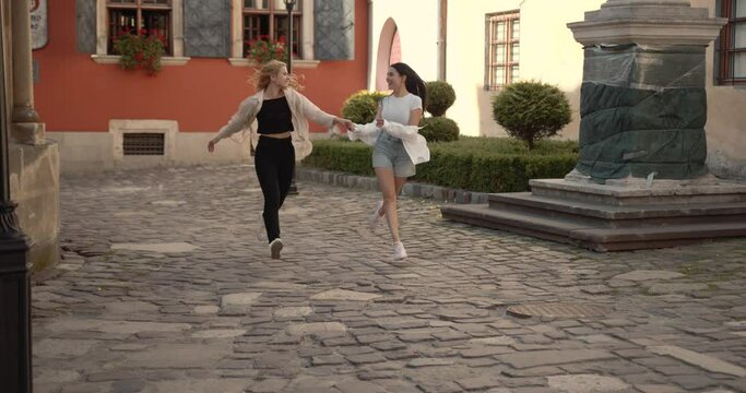 Two lesbians running in the old town holding hands