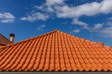 Red tiles panels roof under blue sky.