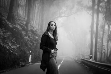 Beautiful young woman with freckles on a foggy road.