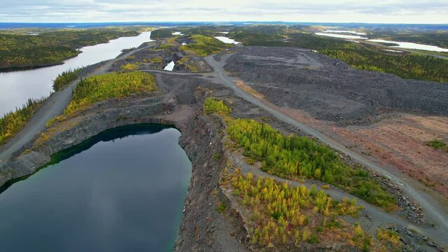 Aerial flyover of water-filled open pit mine excavation in a historical gold mine in northern Canada