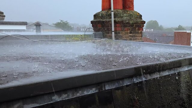 Heavy rain downpour on a flat residential roof.  Real time, zoom out.