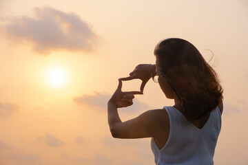 Woman covering her hands, posing, framing frame, with sunset Planning and foreseeing the future