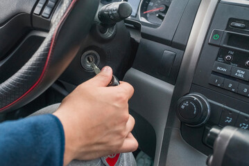 Hand of a person inserting the key to start the engine of a car.