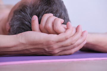 Close-up of hand of man over his head while lying on a gym mat