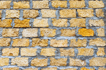 Stone bricks from limestone laid, cement, yellow brown background texture. Natural rough stone wall texture, front view, full frame, close-up