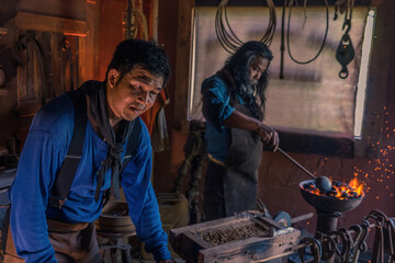 blacksmith is smelting iron to make horseshoes.hot iron on the anvil ready to be beaten to make a...