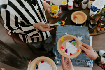 A crafts and arts teacher is giving their students paint for mixing and then painting