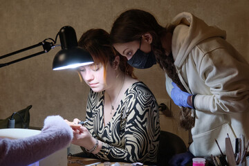 A young woman mentor teacher coach conducts individual training in manicure techniques.