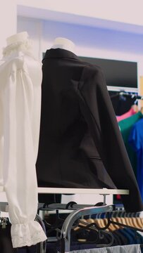 Vertical video: Shopping mall boutique filled with fashion tailoring, multiple racks with fashionable formal wear. Empty clothing showroom with trendy shirts on hangers, small business concept.