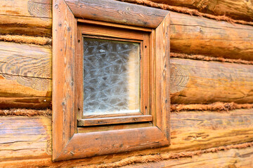 log wall, corner of a wooden house and a window