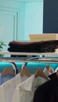 Vertical video: Empty fashion showroom for shopaholic customers, small business concept with merchandise in clothing boutique. Fashionable collections of formal wear in retail market shop, consumerism