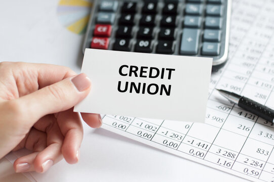 Credit Union text on a card in the hand of a businessman on the background of an office desk, a business concept