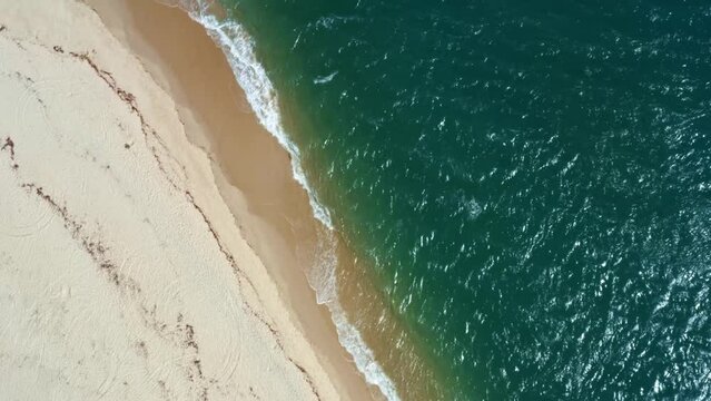Rotating birds eye top aerial drone shot of the tropical Rio Grande do Norte, Brazil coastline with golden sand, turquoise clear water, and small calm waves in between Baia Formosa and Barra de Cunhaú
