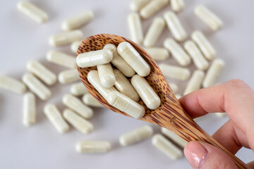 Beige cold and flu capsules in a wooden spoon. Supplements and medications. Close-up, top view.