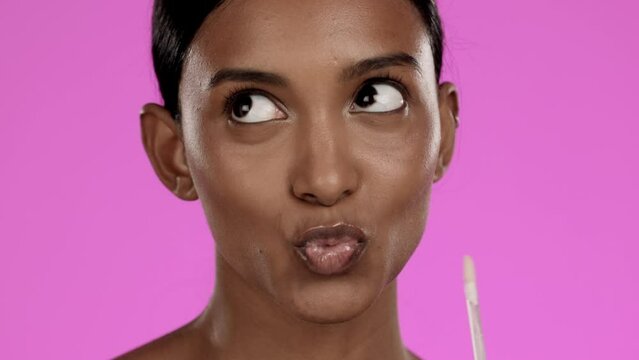 Beauty, makeup and Indian woman in studio with lip gloss, cosmetics and isolated on pink background. Natural skincare, moisturiser and portrait of model lips with kiss, luxury lipstick color product.