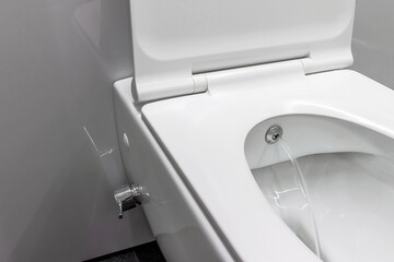 Toilet bowl with control bidet. Water sprays from the toilet bowl. A cleansing jet of water...