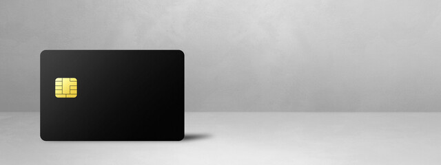 Black credit card on a white concrete background