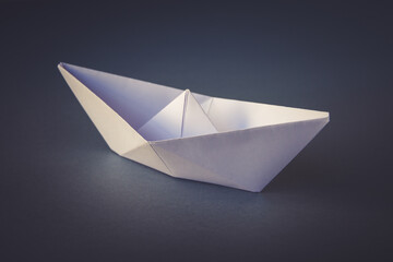 White paper boat origami isolated on a grey background