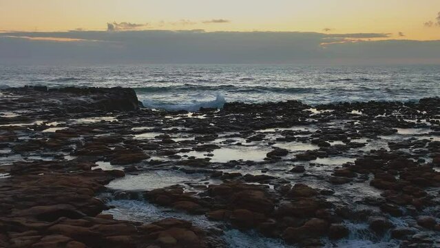Sunrise at the seaside with tessellated rock platform in North Avoca on the Central Coast, NSW, Australia.