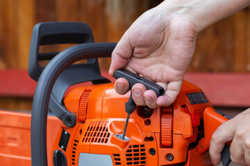 The process of starting a chainsaw. A male worker pulls the starting cable of a chainsaw with his...