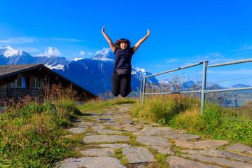Happy woman jumping and enjoying life in the mountains. Location place Swiss Alps, Grindelwald valley, Switzerland. Travel and active lifestyle concept