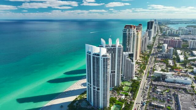 Expensive highrise hotels and condos on Atlantic ocean shore in Sunny Isles Beach city and busy street traffic. American tourism infrastructure in southern Florida