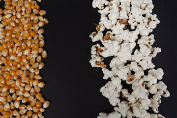 a row of ready-made popcorn and a row of corn kernels on a black background, place for inscription and advertising.