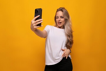 a girl with a phone in her hands takes a photo on a yellow background