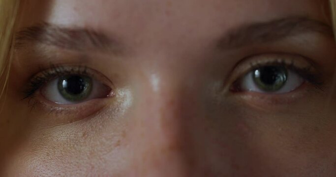 Close Up Macro Zoom Shot of an Eye. Young Beautiful Female Looking at the Camera, With Light Green and Brown Color Pigmentation on the Iris. Mascara is Applied to Eyelashes. Dilating Black Pupil.