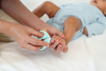 Obraz na płótnie Canvas mother cutting baby's foot fingernails with nail scissors.