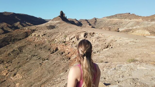 young woman observes the majestic rock formations near the playa del medio Almud on the island of Gran canaria, municipality of Mogan.