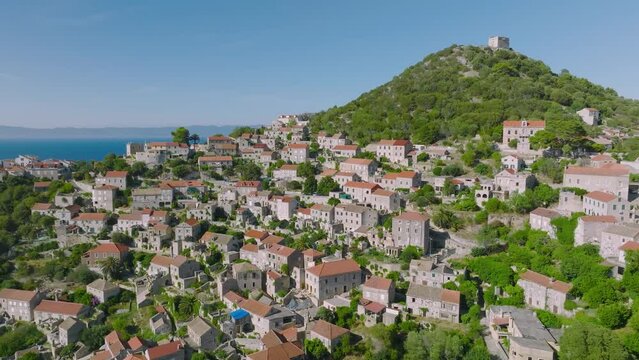 Aerial arcing shot gently circling around the town of Lastovo, Croatia on a bright clear day.