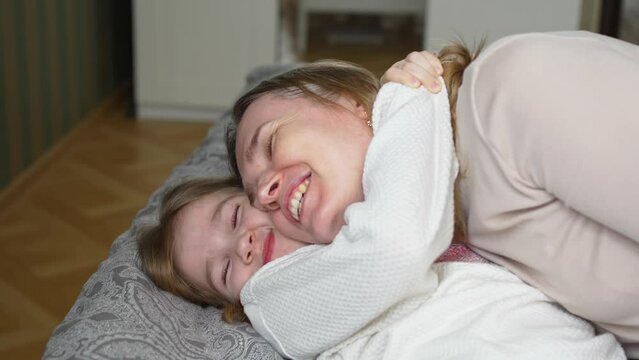 mom and daughter hug, laugh and play in bed. friendship of parents and children.