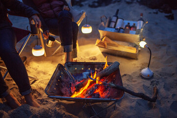 Low section of friends by bonfire at beach