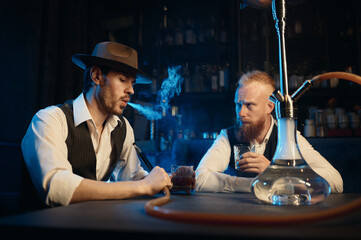 Stylish gangsters smoking hookah in bar having business meeting
