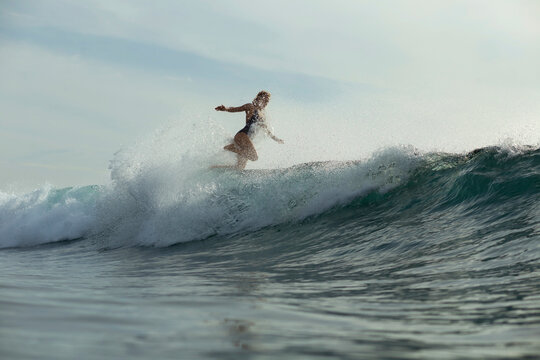 Woman surfing in sea against sky