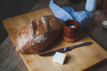 High angle view of loaf of bread with cheese on cutting board over wooden table