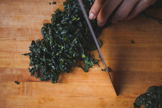 Cropped image of woman hand chopping chard on cutting board in kitchen