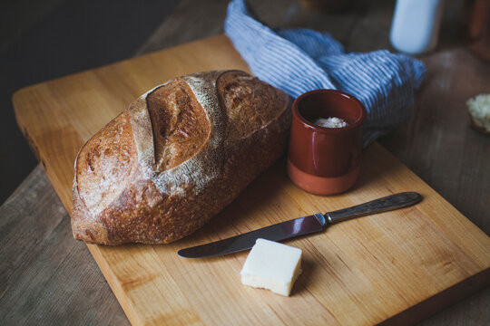High angle view of loaf of bread with cheese on cutting board over wooden table