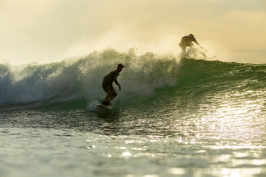 Friends surfing in sea during sunset