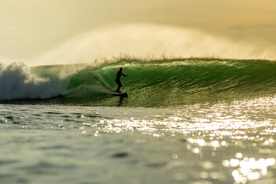 Silhouette man surfing in sea during sunset