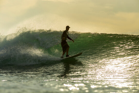 Side view of silhouette man surfing in sea during sunset