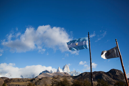 Low angle view of flags by mountain against blue sky